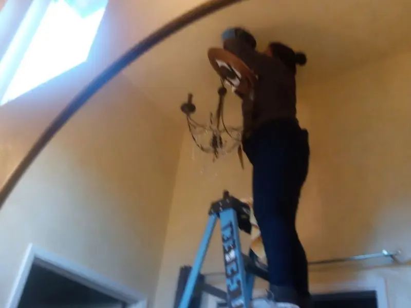 Electrician installing a chandelier in a Wallace residence